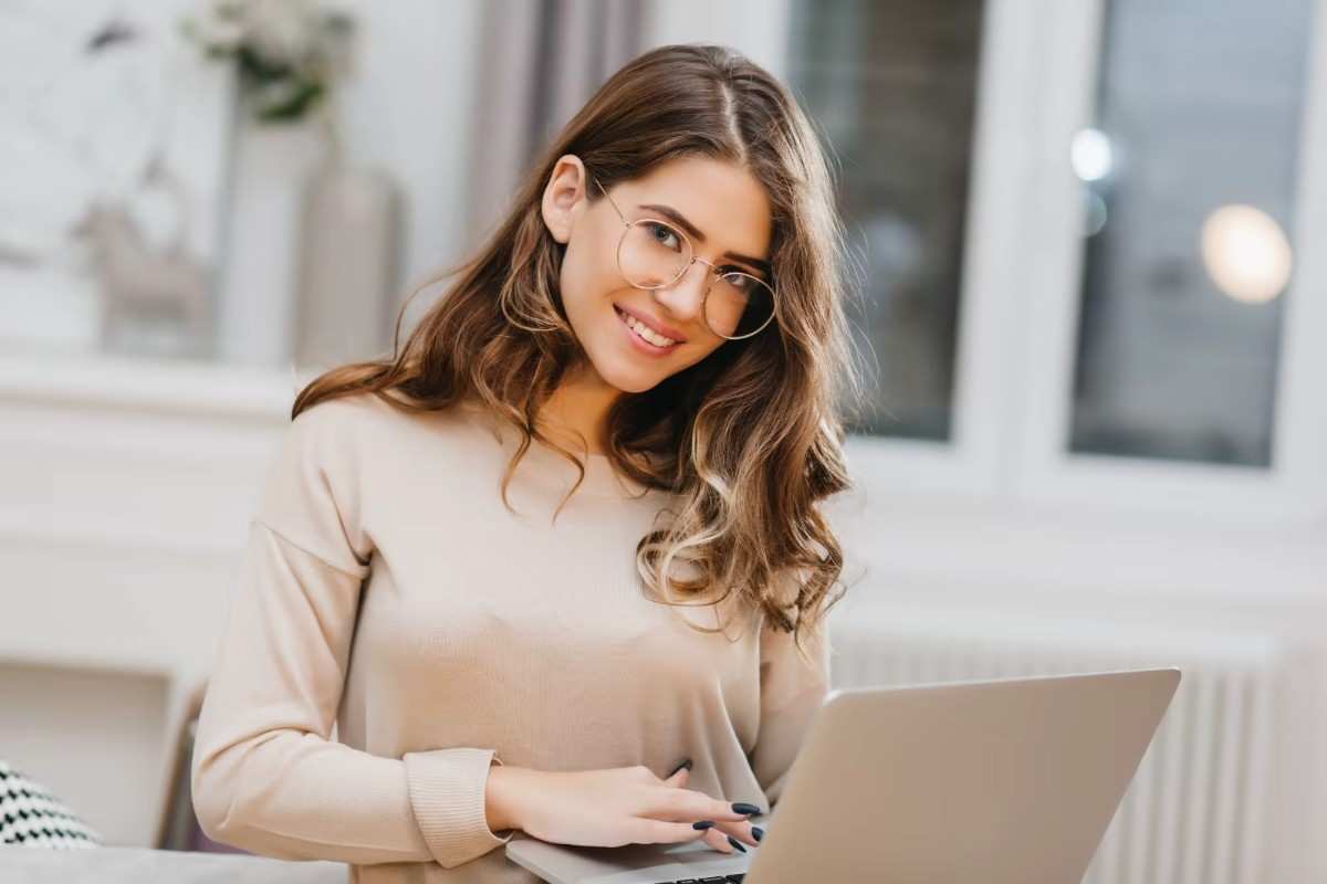 A young woman holding her laptop while standing