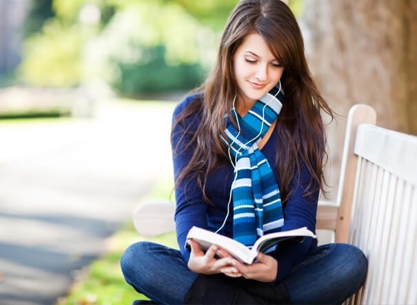A teenage girl sits near the books and thinking about her bright future.