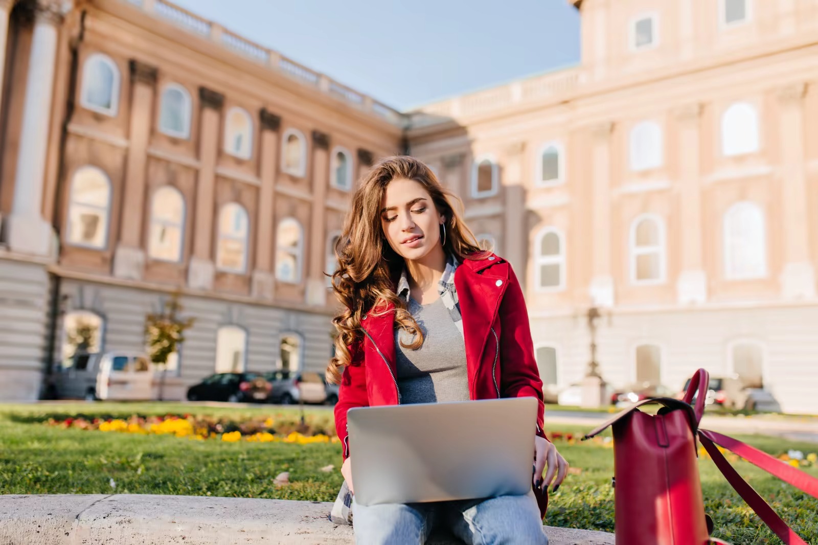 A beautiful woman studies on her laptop while sitting in a public place in order to achieve the highest levels of academic excellence and attend renowned institutions. 