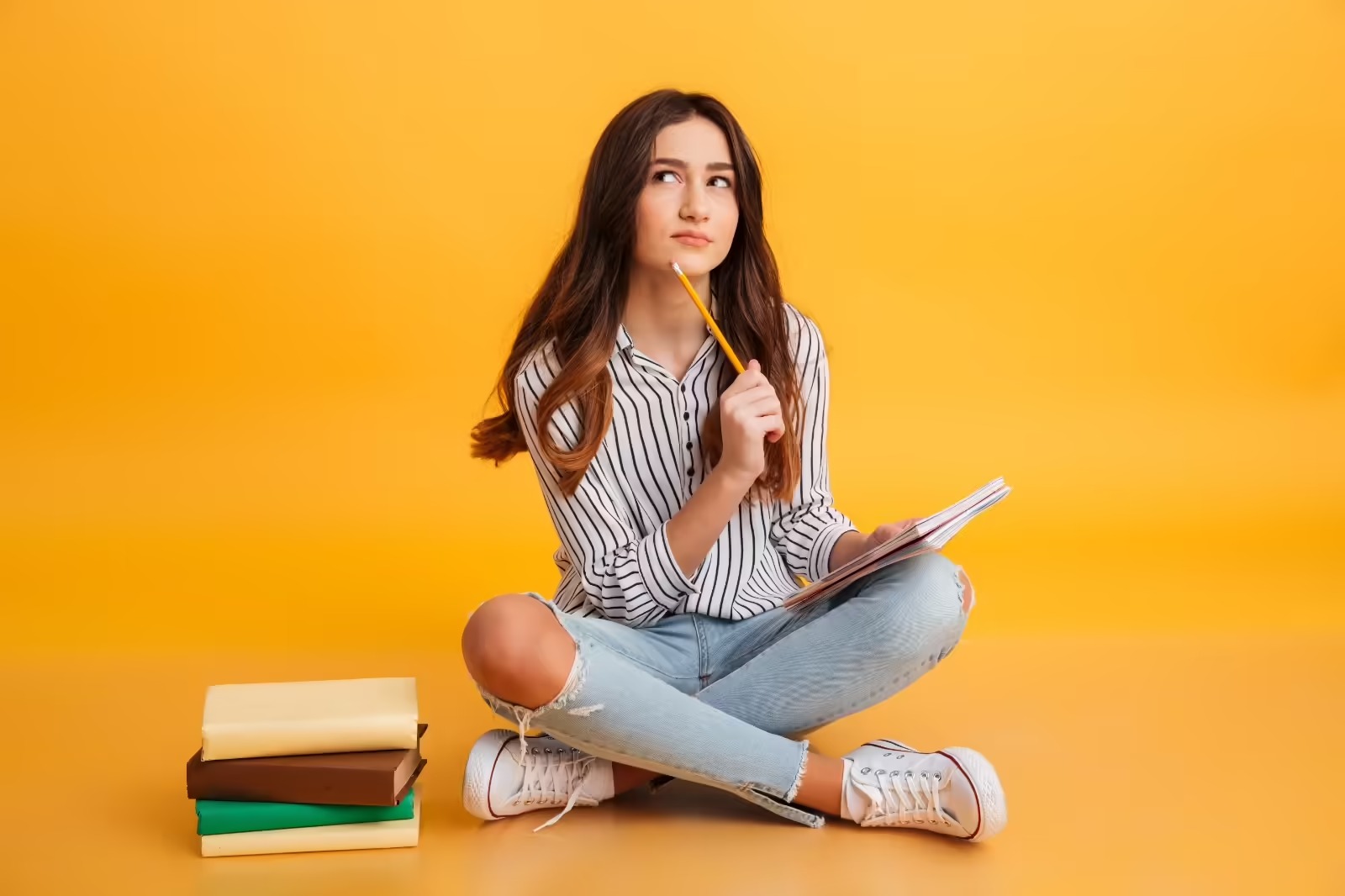 A teenage girl sits near the books and thinking about her bright future.